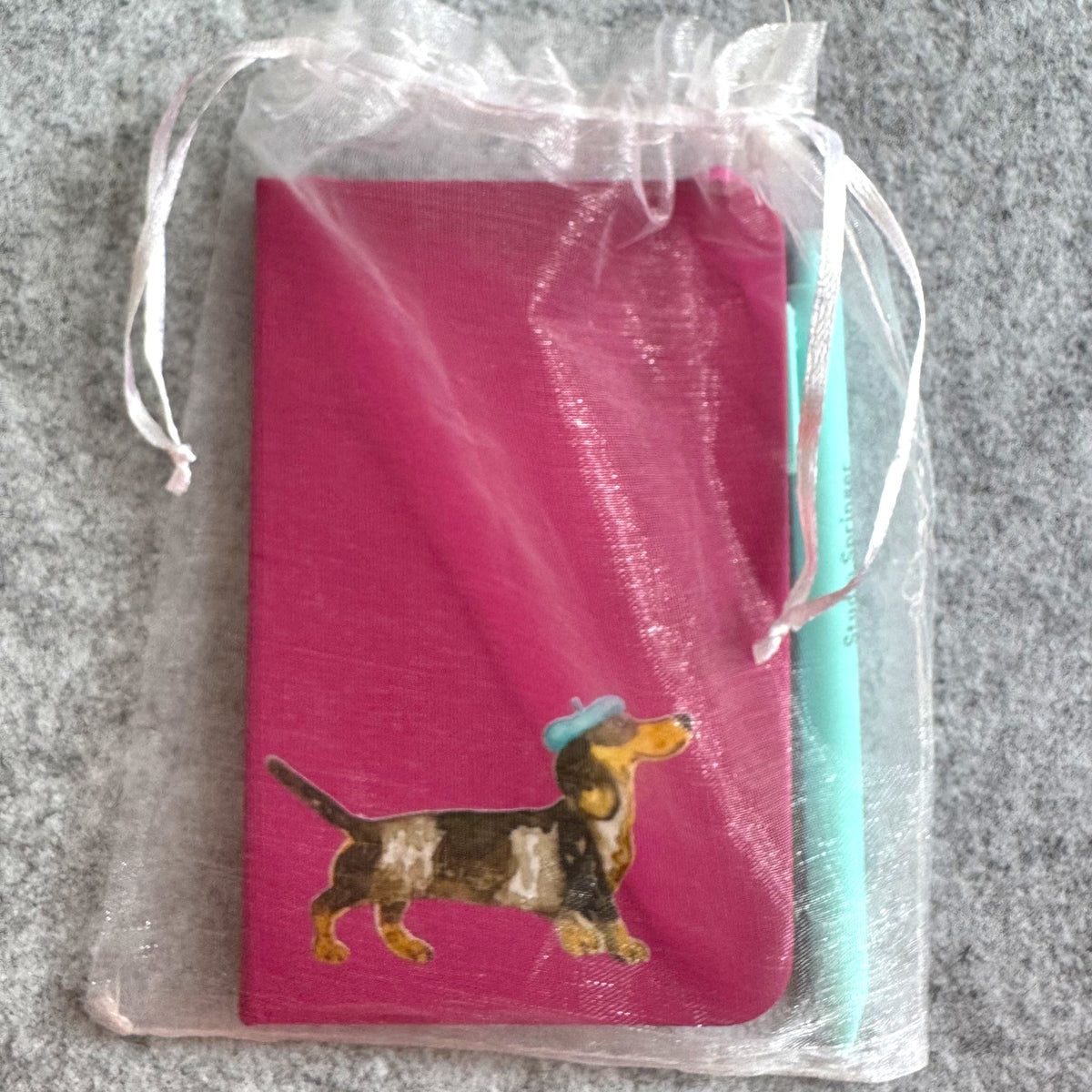 Achterkant van het fuchsia notitieboek met elastische band en Studio Springer-logo